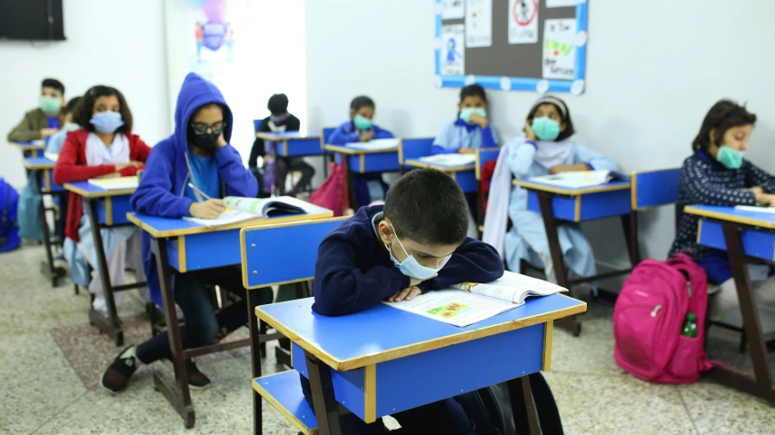 a school with children wearing masks and writing