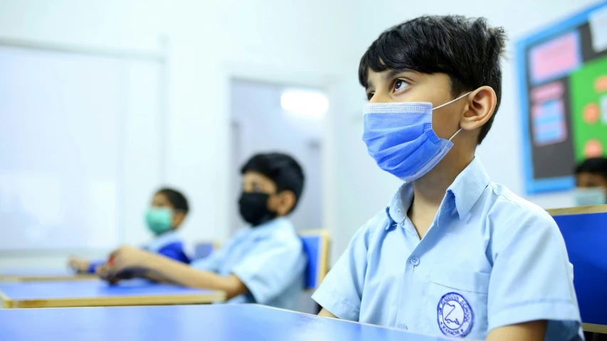 a child wearing a surgical mask sitting at a table