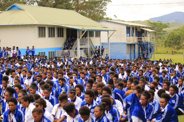 a large group of people wearing uniforms walk together in front of some houses