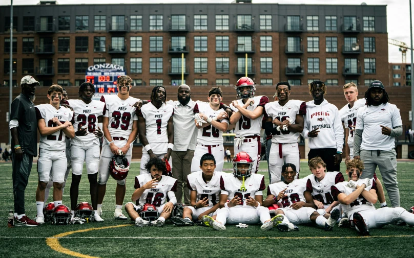 football team posing on a field with trophy