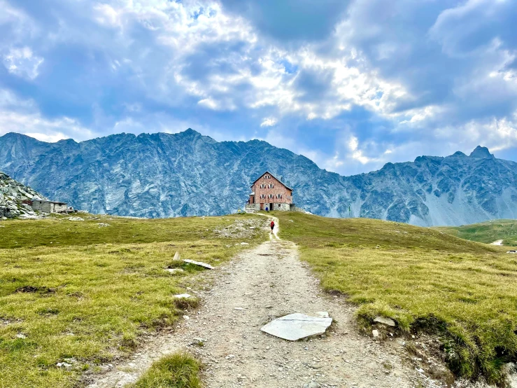 a dirt path between grass with mountains in the background