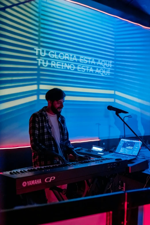 a man is sitting at a keyboard in front of a microphone