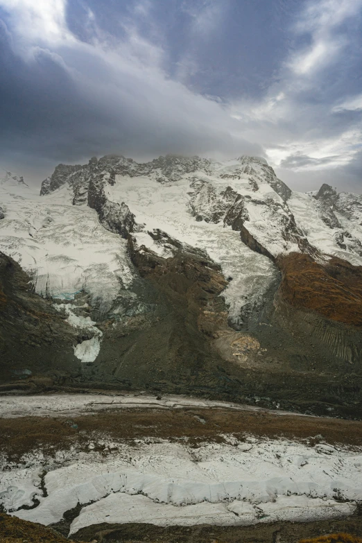 the snow covered mountains are seen under a cloudy sky