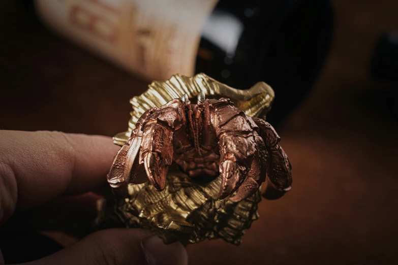 a person holding a small gold piece next to a bottle