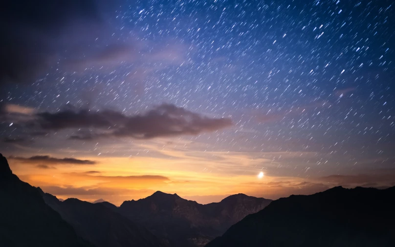a mountain with lots of stars and the sun above it