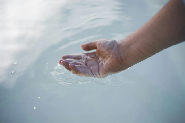 hand reaching for soing out of water that is in a body of water