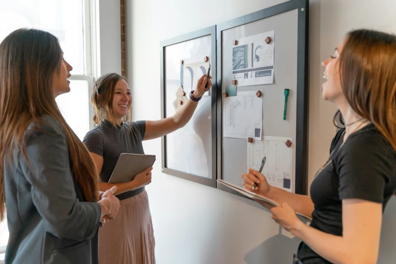 three women with clipboards and binders on a wall