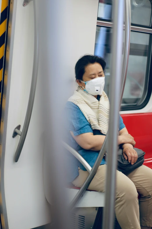 man with surgical mask sitting on bus while looking at cell phone