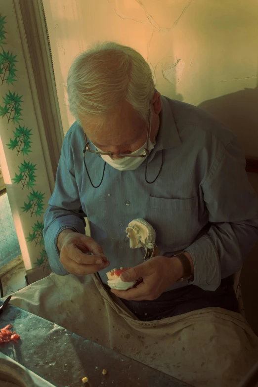 a man sits with food and is wearing a mask