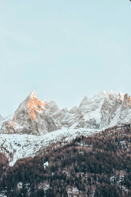 a view from a snowy mountain with a small snow topped peak