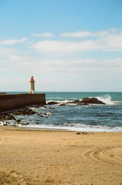 a person walking on a beach with a light house in the background