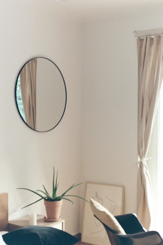 an oval mirror over a chair in a bedroom