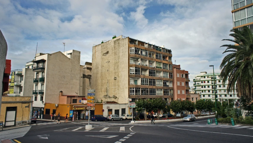 a building is in the middle of a street with palm trees and buildings in the background