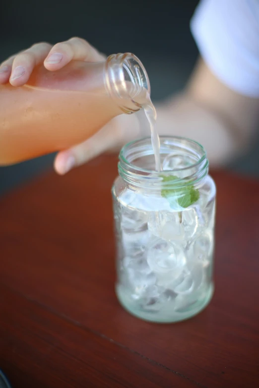 a glass filled with water and ice next to someone