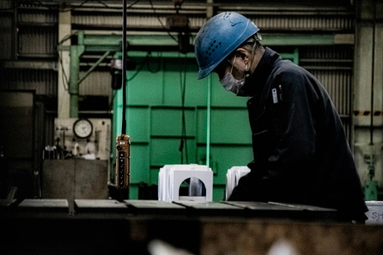 man in blue hard hat operating machine near green building