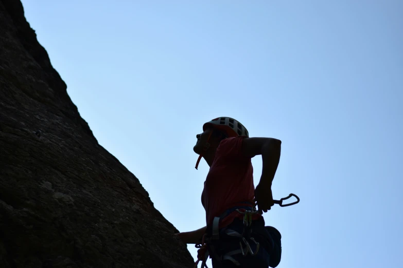 a man is standing on a rock face up with a helmet on