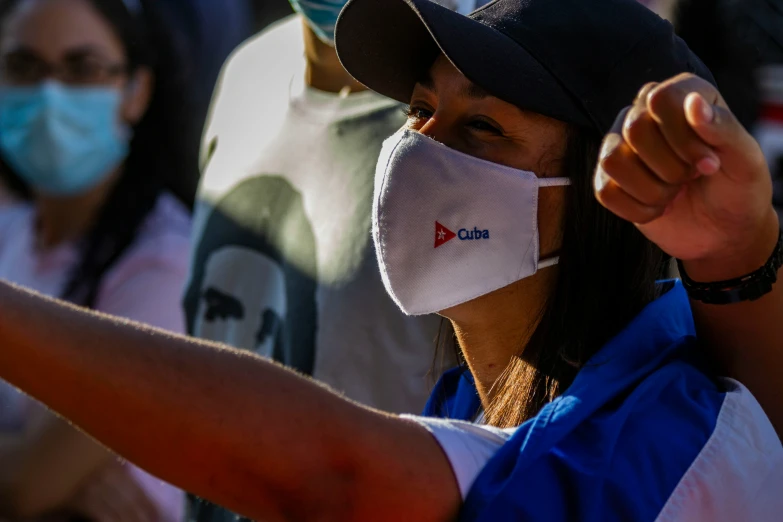 a woman with a face mask on pointing at soing