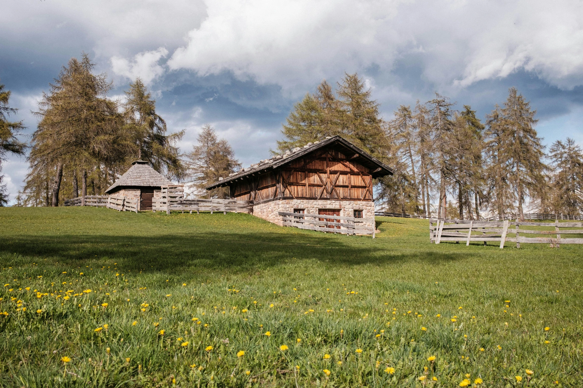 a log house in the field with other wooden barns