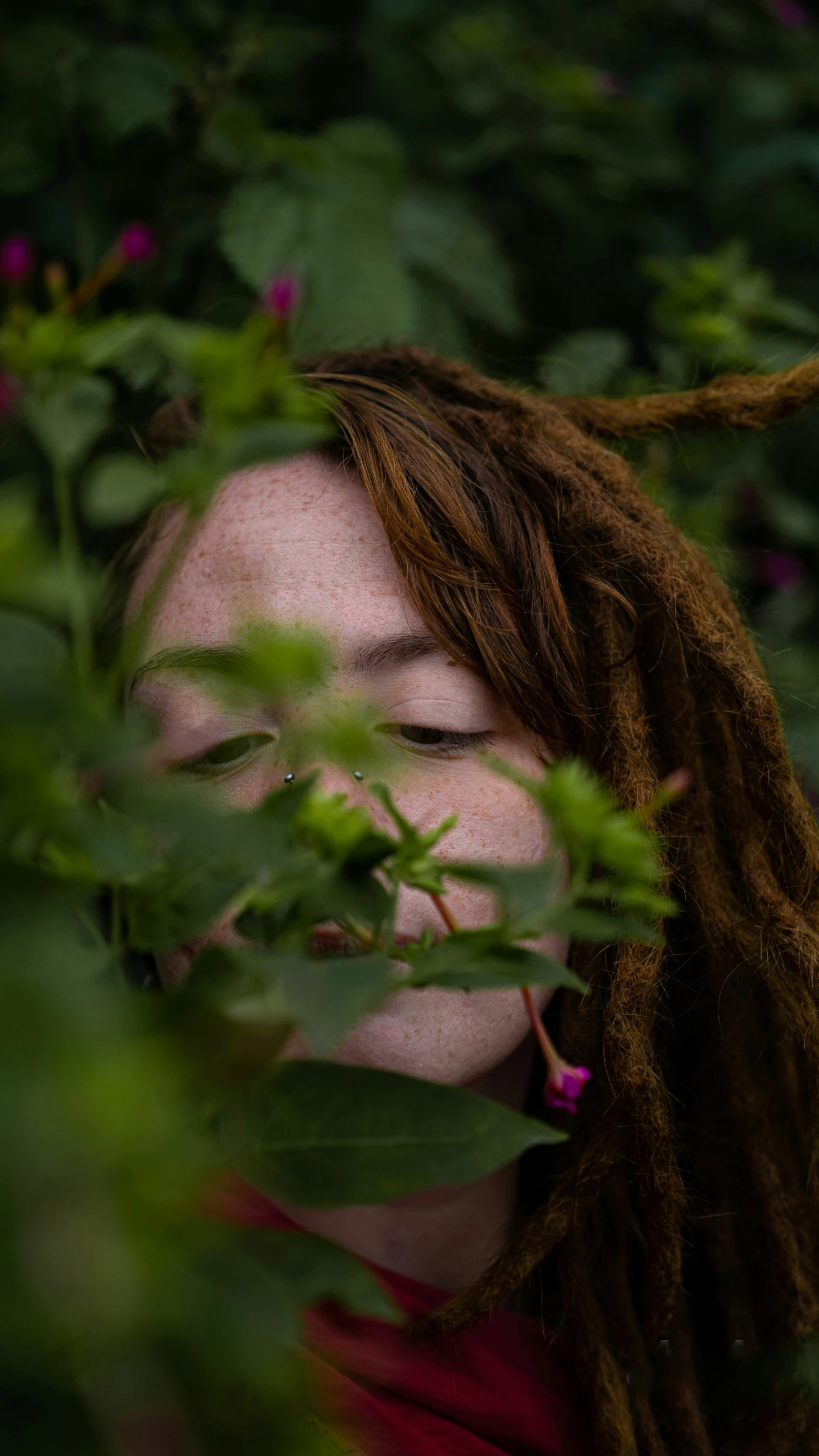 a woman with long dreadlocks is covering her mouth