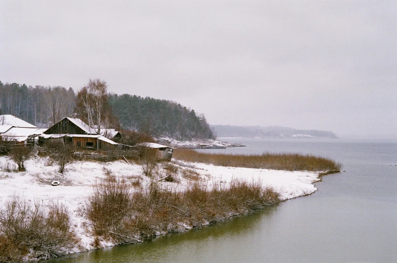 a house sits on the edge of a river during winter