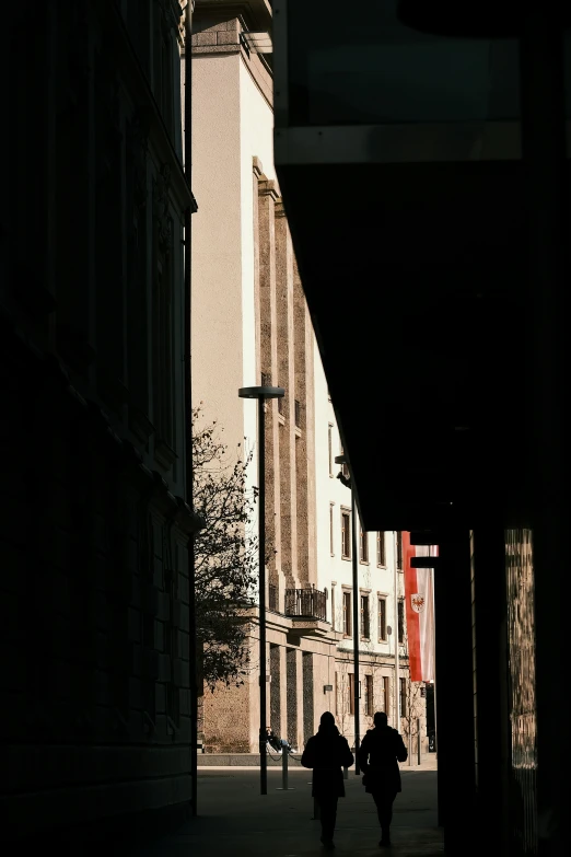 two people walking down the side walk in the dark