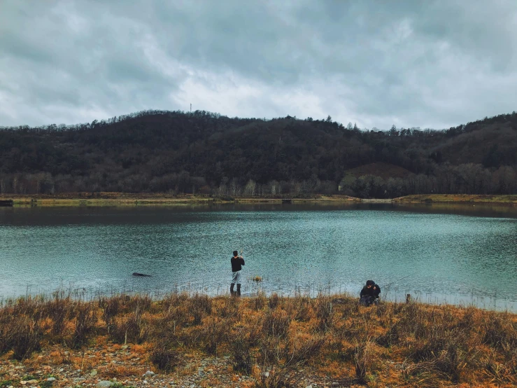 two people walk along side of a pond