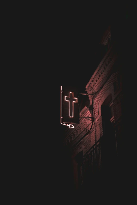 a large lighted cross hanging from the side of a building