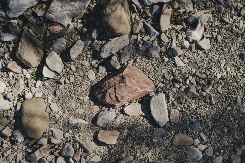 a red rock sitting among rocks on the ground