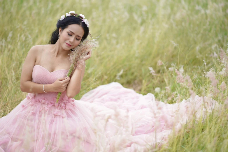 the woman in a pink dress is holding a flower