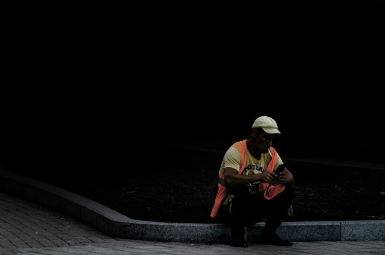 a man in a white hat sitting down while using his cell phone