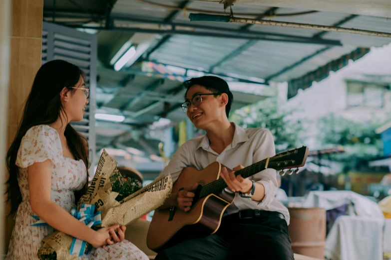 a man holding onto a guitar and talking to a woman