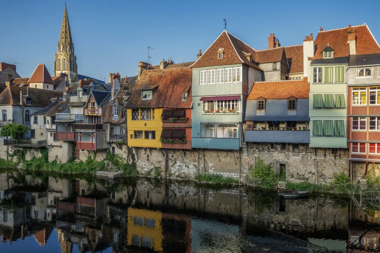 some colorful buildings along a river and one of them has a tall tower