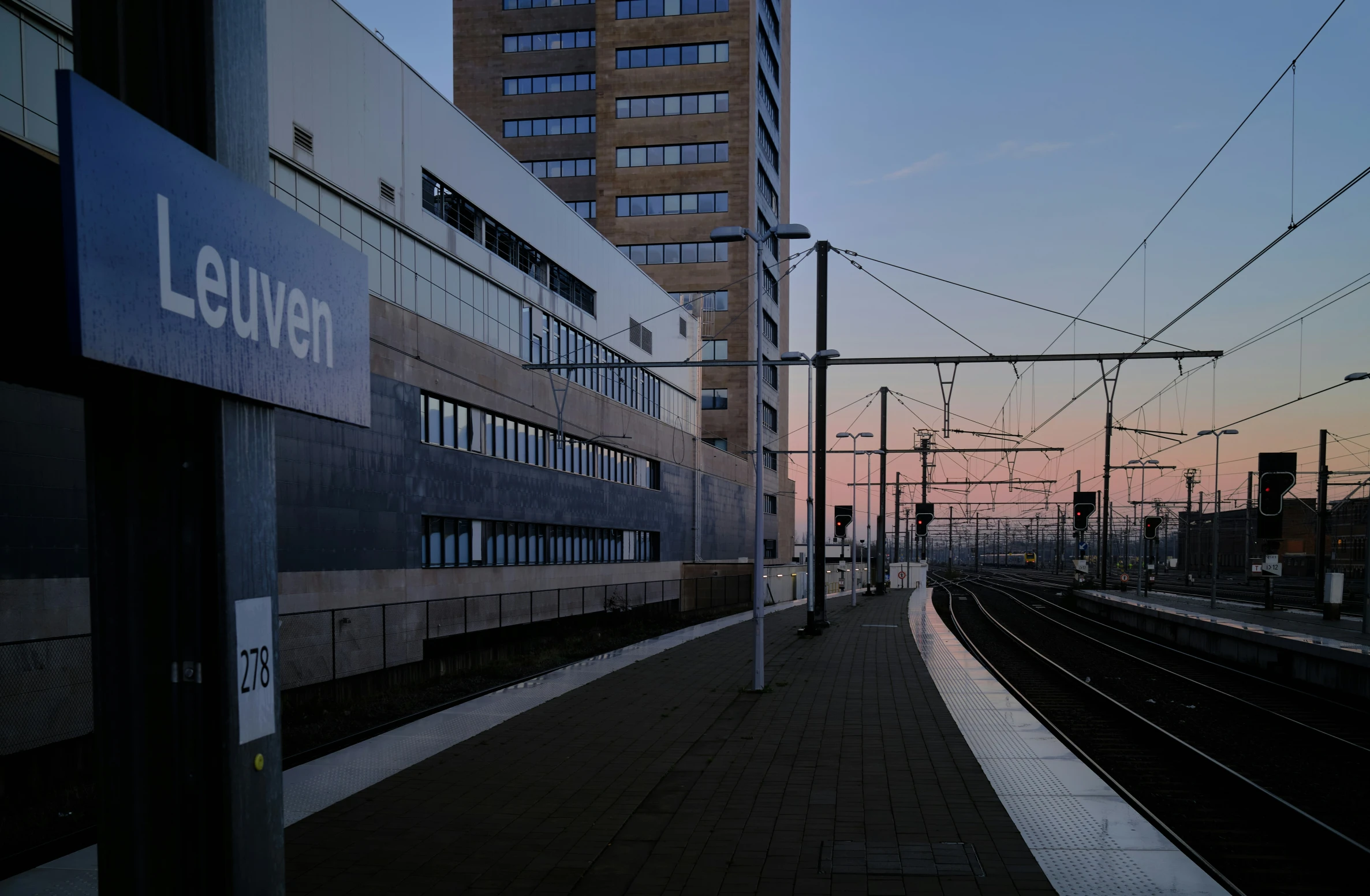a train track next to a building at sunset