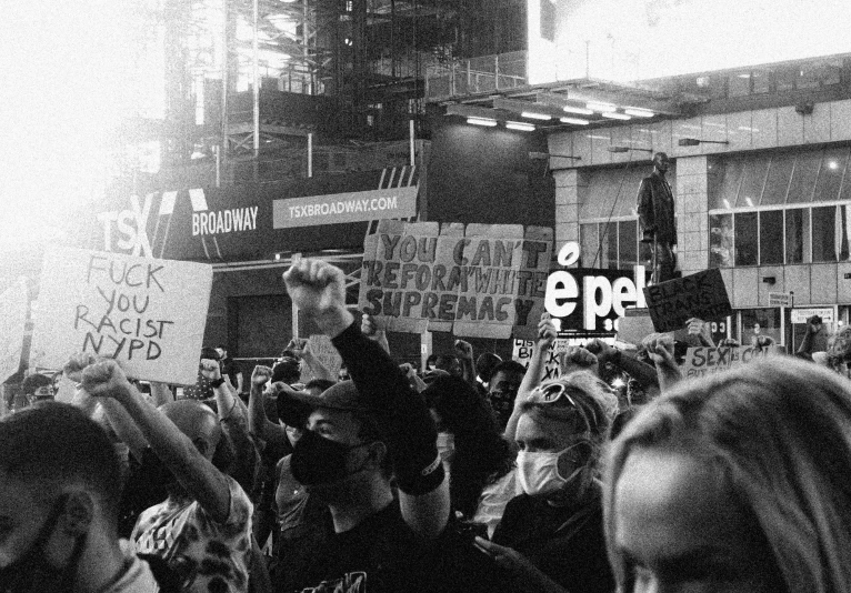 a crowd of people holding signs and standing in the street