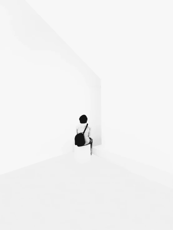 man sitting on chair in white room with white walls