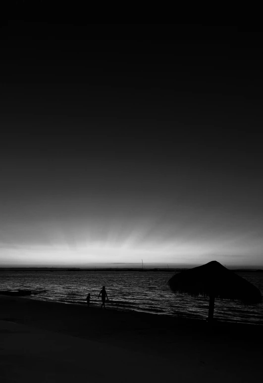 a silhouette of an umbrella on a beach with people