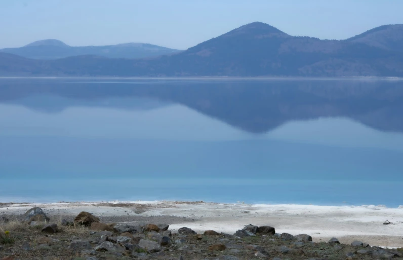 a couple of mountain tops with some water in the foreground