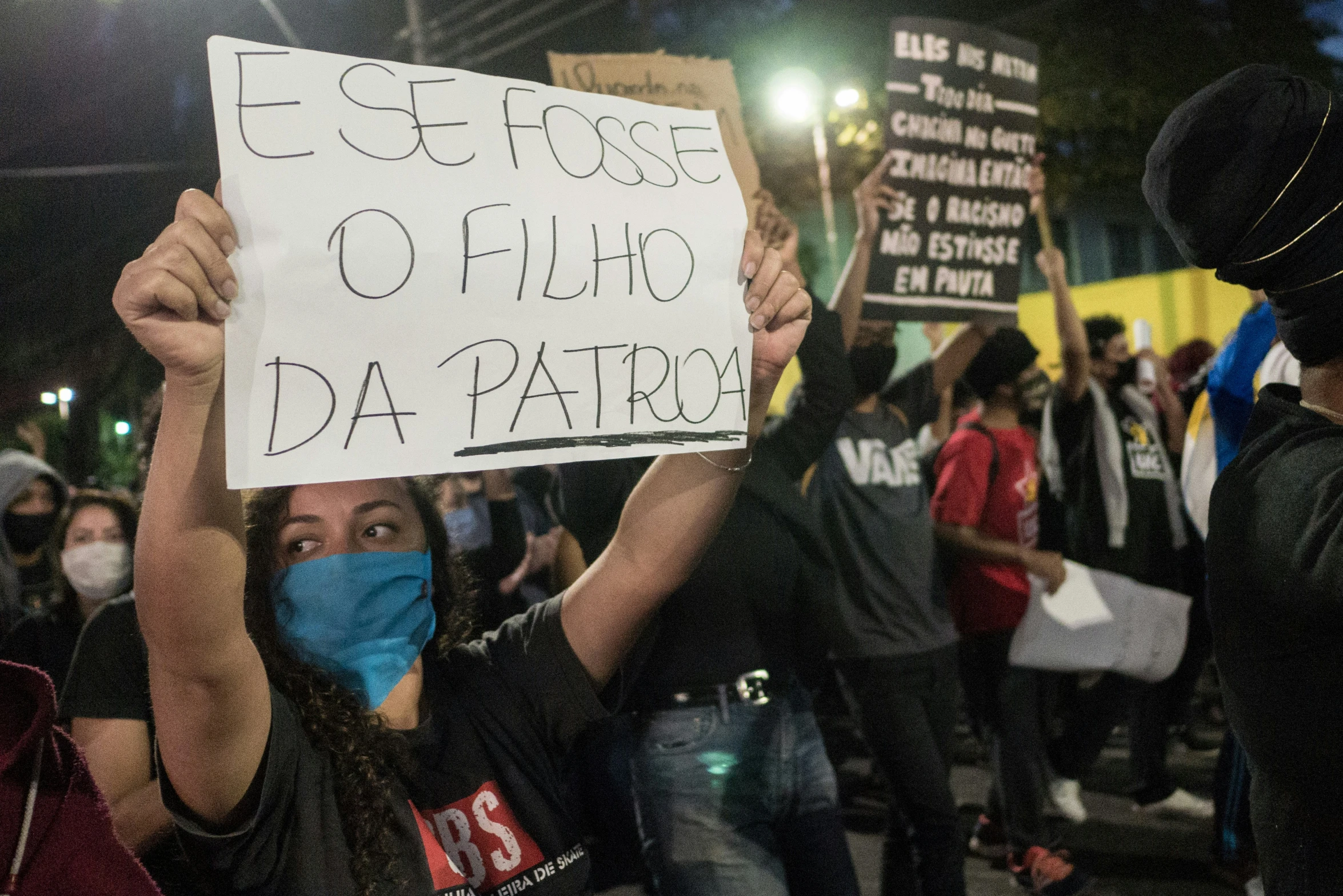 protestors wearing masks are holding signs and talking