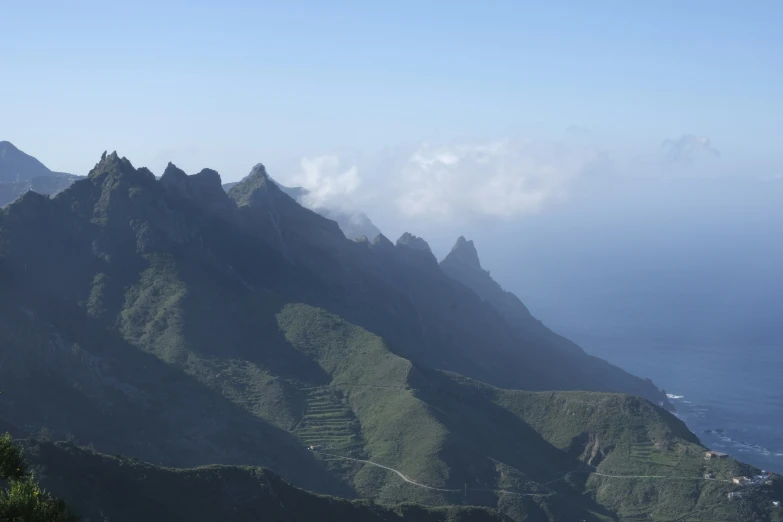 some mountains on a sunny day with some fog coming down