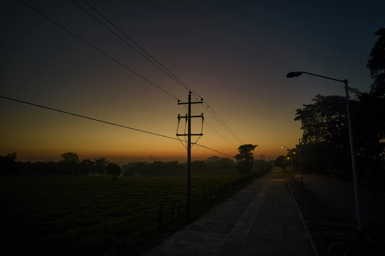 electrical wires that are hanging on poles and in the distance, in the evening