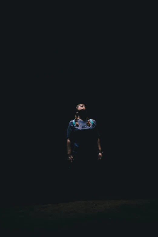 a man standing in the dark with his face slightly up