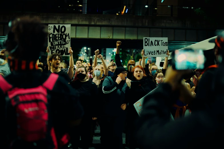 people stand in the dark holding signs and taking pictures