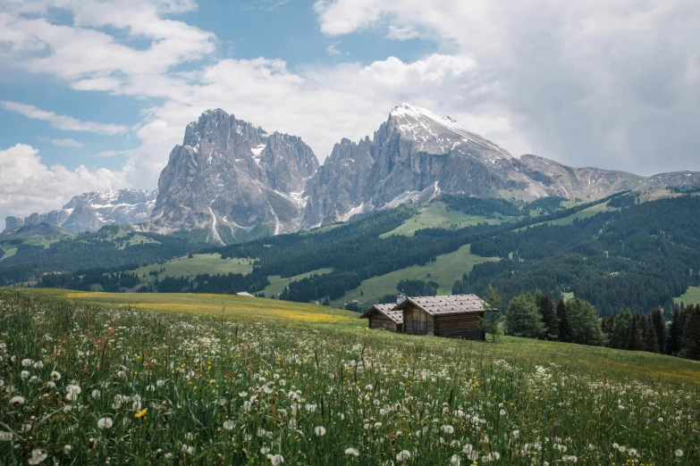 a mountain landscape with a lone shack in the foreground