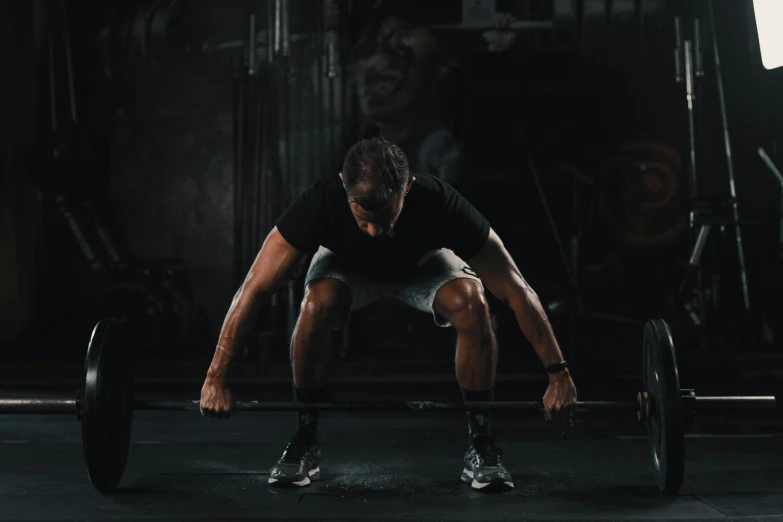 man squatting and lifting weights in the dark