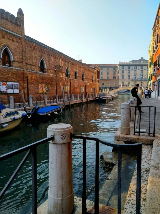 a person on a rail looking down at water with boats in the background