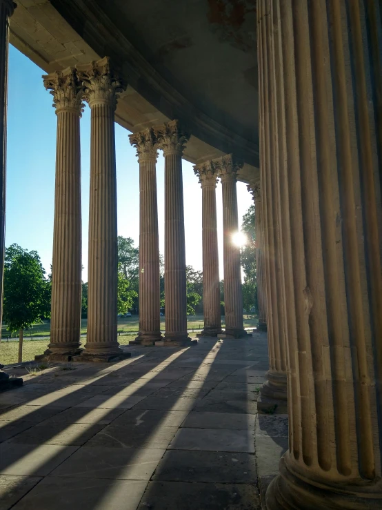 the sun shining on many large columns of a building