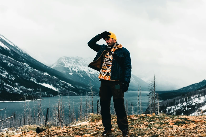 man in yellow hat looking at mountains and lake