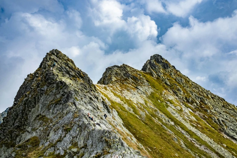 two mountains against a partly cloudy sky in the mountains