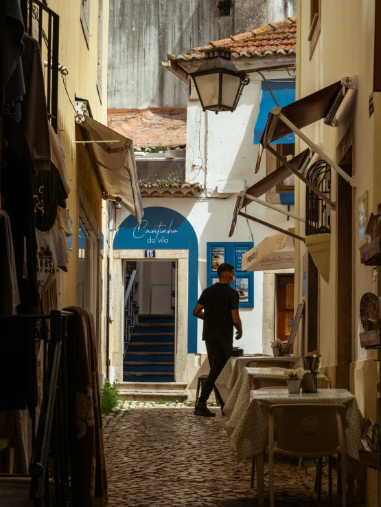 a man walking through an alley way under umbrellas