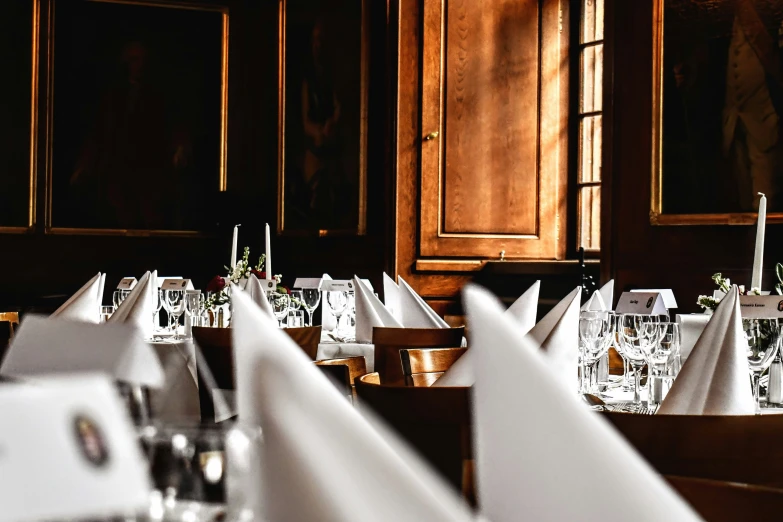 some white napkins are placed on the tables with other silverware